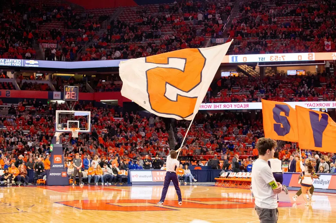 Syracuse University flag being waved on stadium JMA Wireless stadium field.